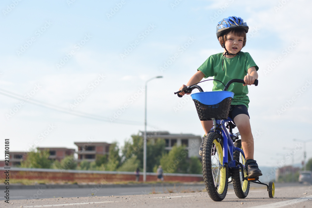 Obraz premium Five years old boy rides a bicycle in the city. Child riding bicycle outdoor on sunny day