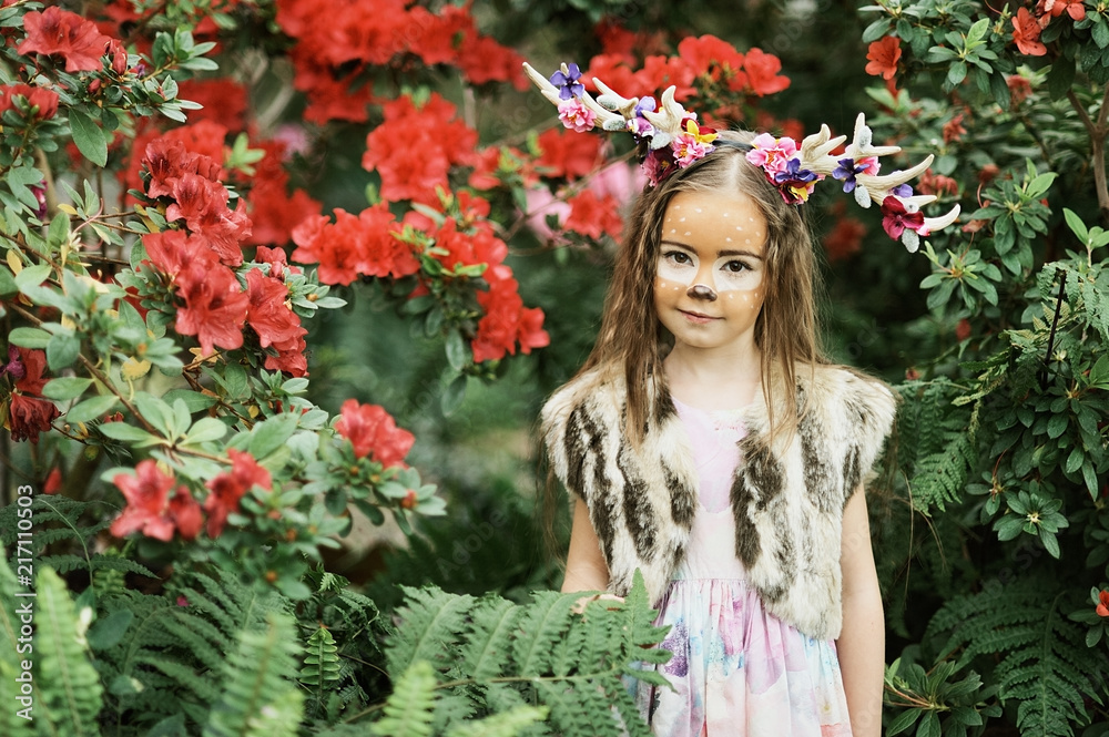 Fairy tale girl. Portrait a little girl in a deer dress with a painted face in the forest. Big antler. Fantasy girl. Springtime. Fairy tale girl. Portrait a little girl in a deer dress with a painted face in the forest. Big antler. Fantasy girl. Springtime.