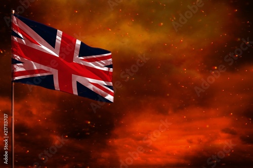 Fluttering United Kingdom (UK) flag mockup with blank space for your text on crimson red sky with smoke pillars background. Troubles concept.