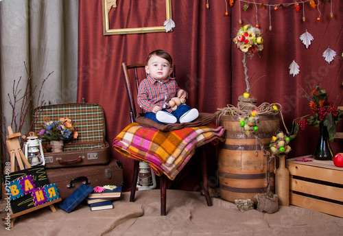 Cute kid in corduroy pants and checkered shirt on the high chair with a rug © dymytrov