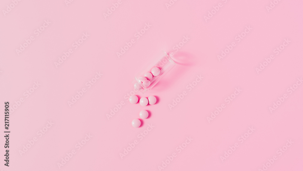 top view of pink medicines spilled from bottle on pink tabletop top view of pink medicines spilled from bottle on pink tabletop
