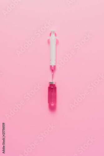 top view of syringe with ampule of pink liquid on pink surface © LIGHTFIELD STUDIOS