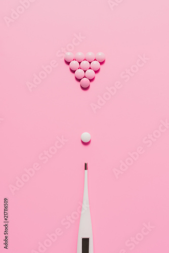 Photos top view of pills with electric thermometer arranged in billiard composition on