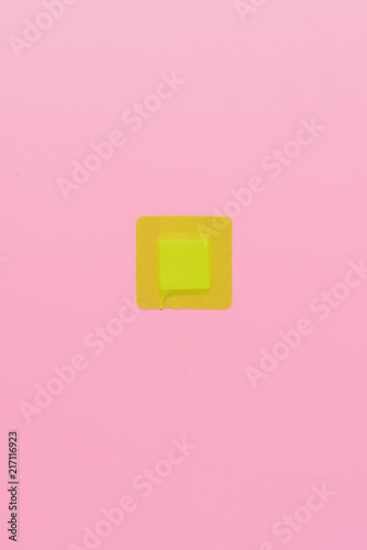 top view of green square adhesive bandage on pink
