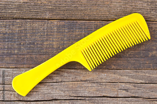 Foto Plastic yellow comb on wooden background