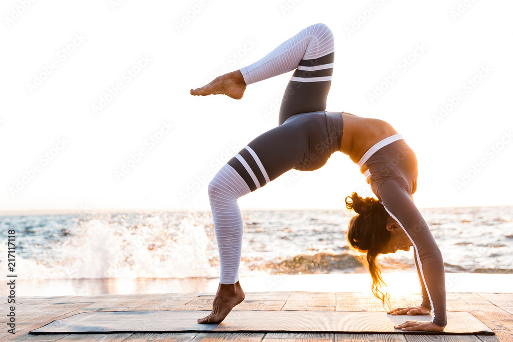 Fototapeta Silna młoda kobieta fitness ćwiczenia rozciągające.