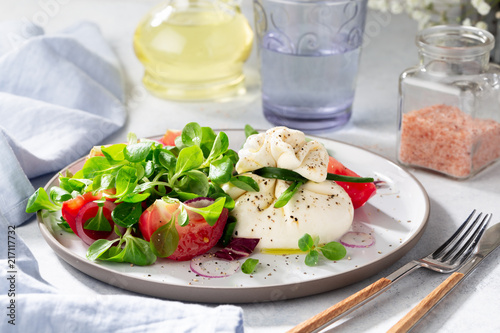 Salad with burrata cheese, tomatoes and corn salad.   photo