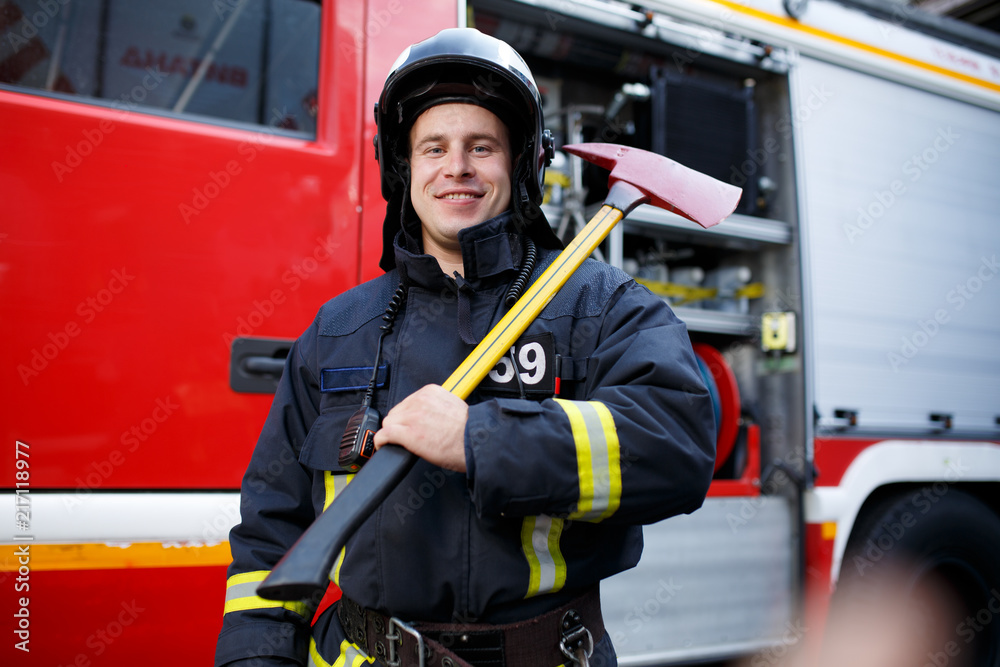 Photo of happy fireman with hammer against fire machine Photo of happy fireman with hammer against fire machine