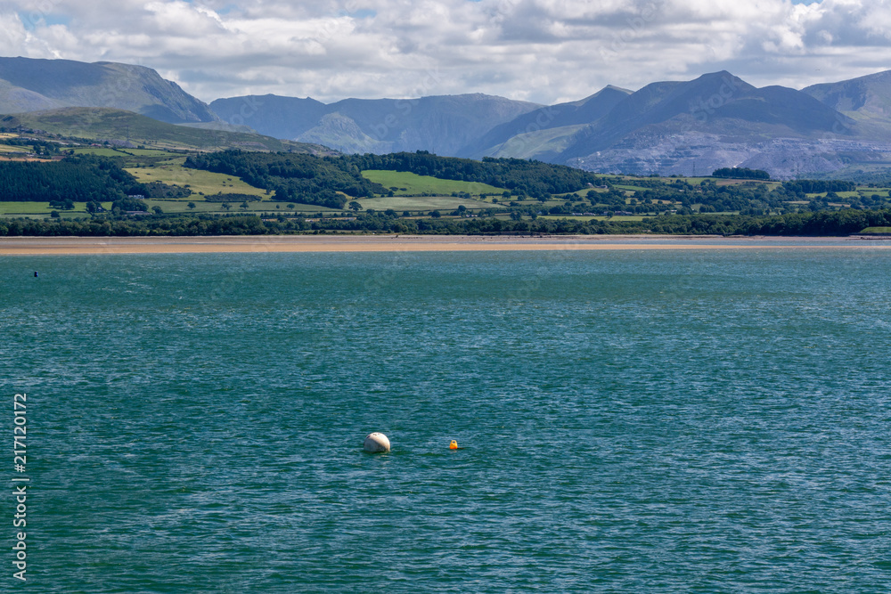 Tidal water of Menai Strait and Snowdonia mountains in the background in summer