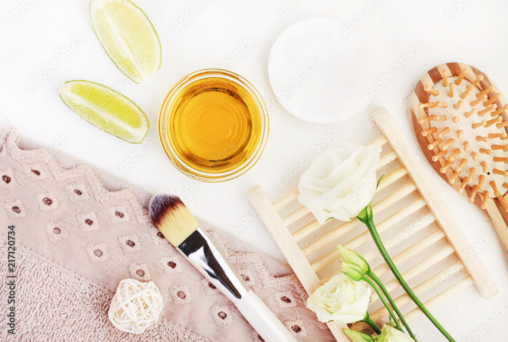 Organic ingredients for homemade spa and hair care with essential oil, lime, aroma flowers. Wooden beauty treatment accessories top view with bathroom towels. Organic ingredients for homemade spa and hair care with essential oil, lime, aroma flowers. Wooden beauty treatment accessories top view with bathroom towels.