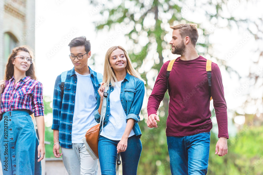 portrait of group of multiethnic students with backpacks walking in park portrait of group of multiethnic students with backpacks walking in park
