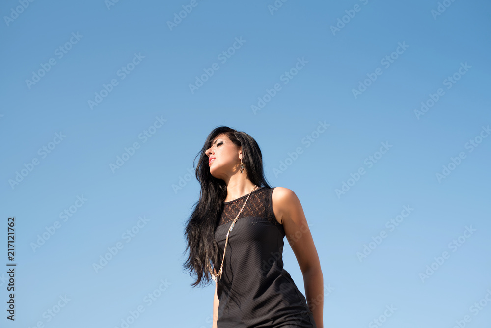 Fototapeta premium Fashion happy young woman on sky background