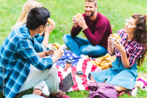 multiracial students with burgers and american flag resting in park © LIGHTFIELD STUDIOS
