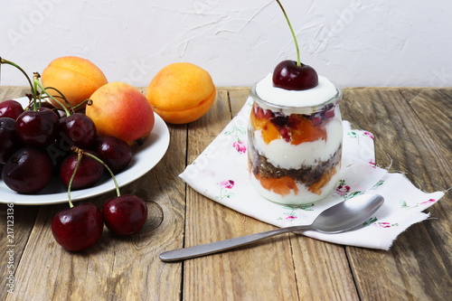 Glass dessert made of yogurt, granola, apricots and cherries