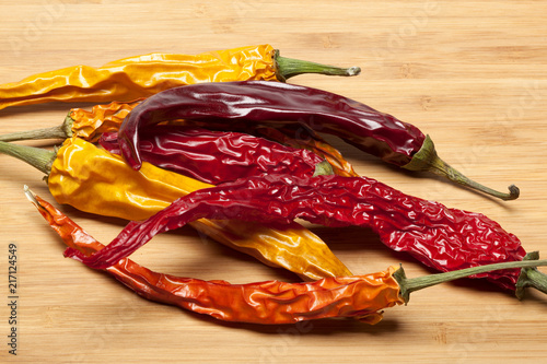 Dried chili pepper in different colors on a wooden background