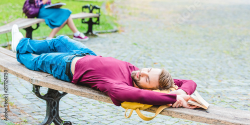 selective focus of student sleeping on wooden bench in park
