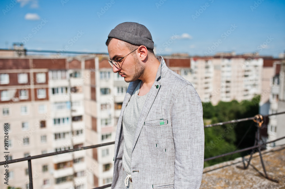 Dreamer stylish macho man in gray suit, hat and glasses posed on the roof. Dreamer stylish macho man in gray suit, hat and glasses posed on the roof.