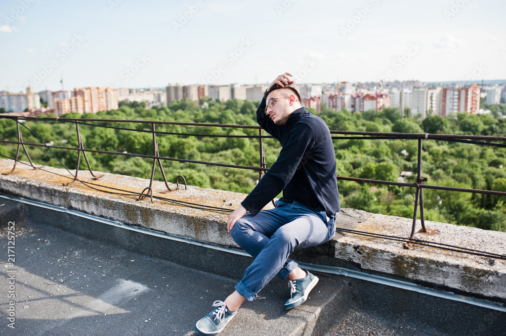 Dreamer stylish macho man in black golf and glasses posed on the roof. Dreamer stylish macho man in black golf and glasses posed on the roof.