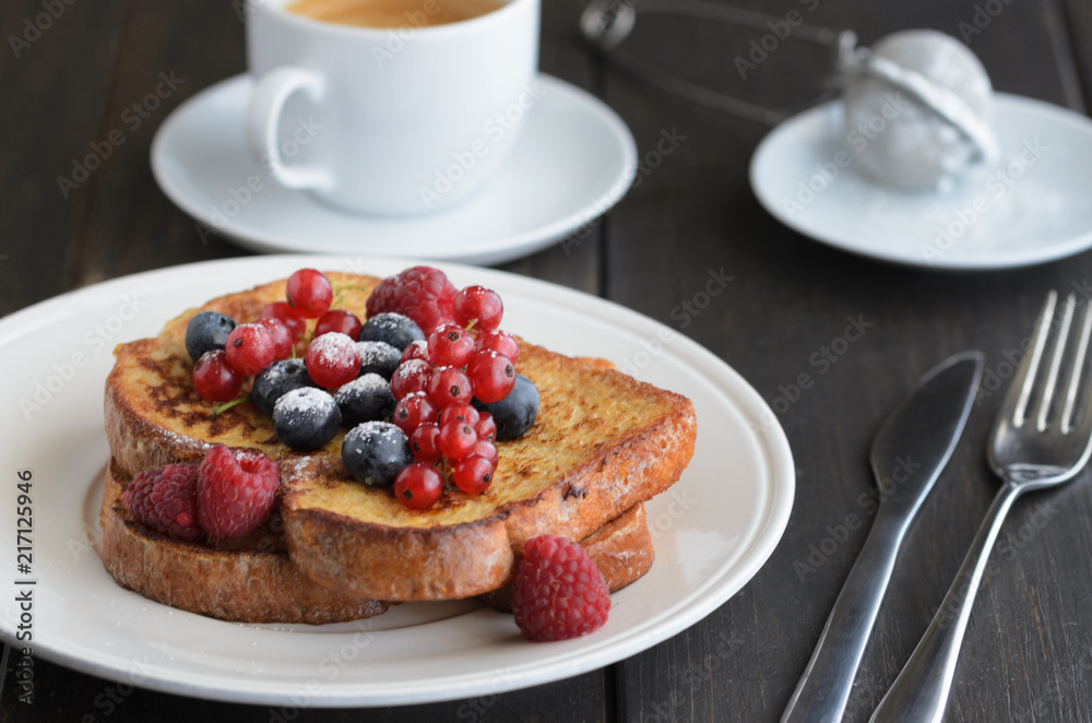 Good breakfast background. French toasts with berries and icing sugar cup of coffee on wooden table. Good breakfast background. French toasts with berries and icing sugar cup of coffee on wooden table.
