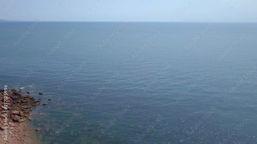 Aerial, flying over a grassy bluff out into infinite blue bay waters Aerial, flying over a grassy bluff out into infinite blue bay waters