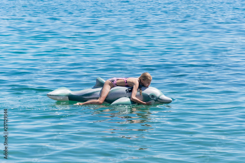 The girl is swimming on an inflatable toy-dolphin on the sea of the ocean. Rest on the water, vacation.