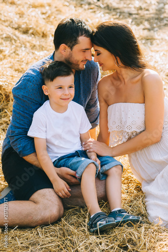 parents and son sitting on hay at farm © LIGHTFIELD STUDIOS