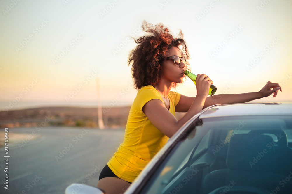 Girl drinking a beer while relaxing after traveling by car