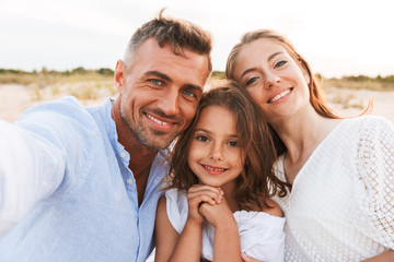 Family outdoors at the beach take a selfie by camera.