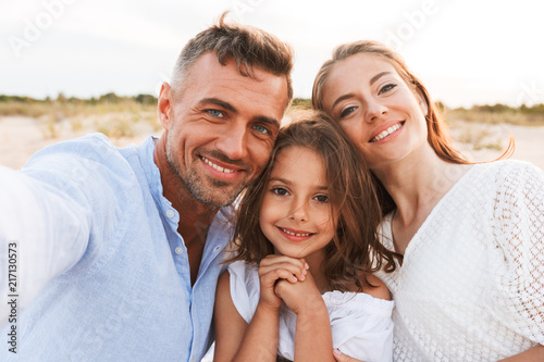 Family outdoors at the beach take a selfie by camera.