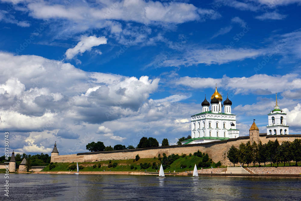 View of the river Church and ancient fortress. Kremlin in Pskov, Russia. Ancient fortress. The Golden dome of the Trinity Church. Beautiful blue sky with clouds.