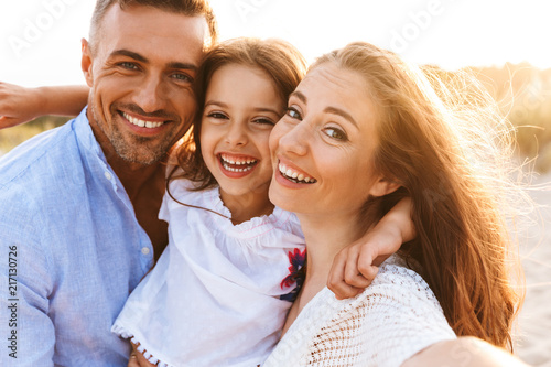 Parents having fun together outdoors at the beach with their daughter.