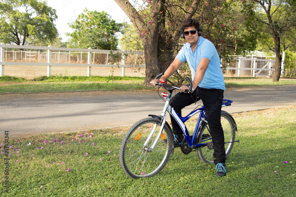 Young man wearing goggles riding bicycle and listening to music