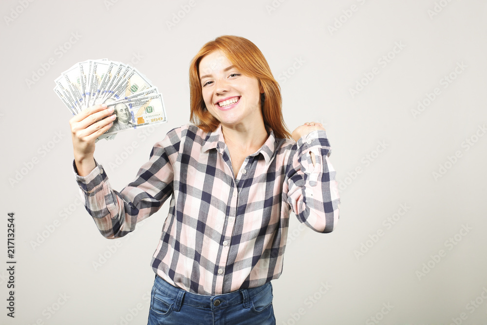 Portrait of cheerful young woman holding bunch of one hundred dollar bills and celebrating in winning pose, hands up raised fist. Beautiful female with lots of cash. Background, copy space, close up Portrait of cheerful young woman holding bunch of one hundred dollar bills and celebrating in winning pose, hands up raised fist. Beautiful female with lots of cash. Background, copy space, close up
