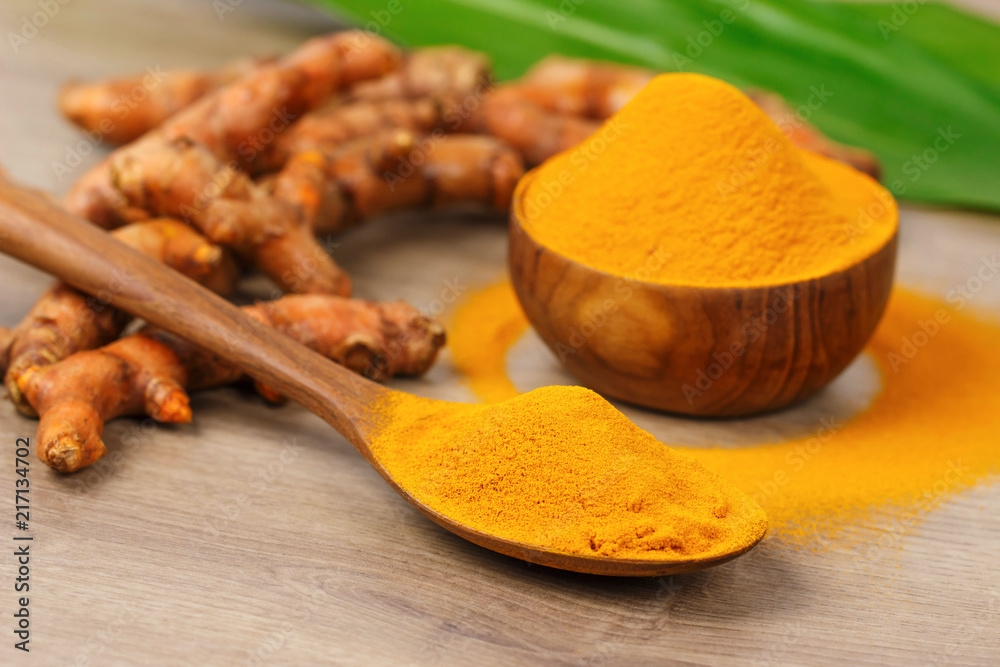 Turmeric powder in wooden bowl and fresh turmeric on old wooden table. Indian Spices Turmeric powder in wooden bowl and fresh turmeric on old wooden table. Indian Spices