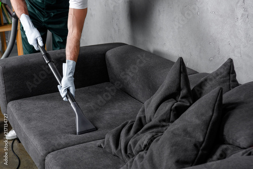 Fotografija Cropped shot of man in rubber gloves using vacuum cleaner and cleaning sofa