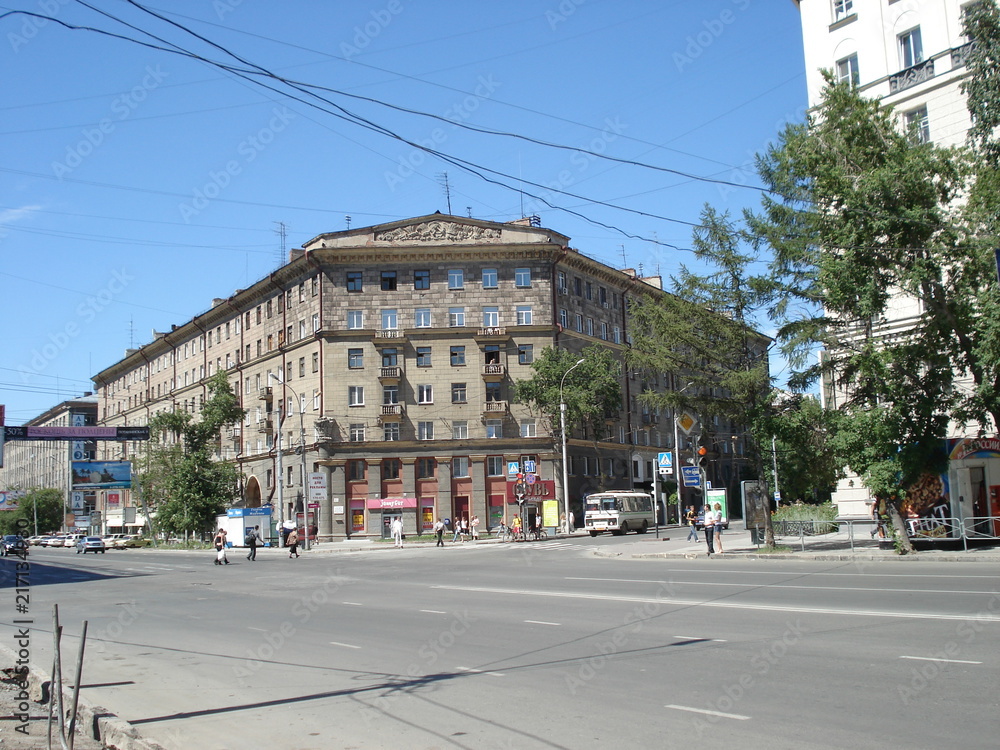 multi-storey building of a triangular shape at the intersection of two streets against the blue sky