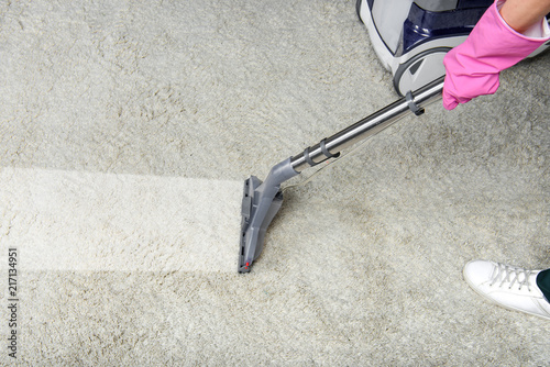Cropped shot of person cleaning white carpet with vacuum cleaner