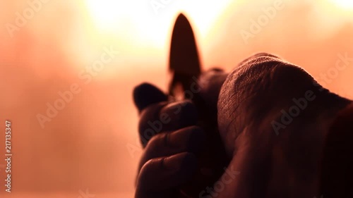 Male holding knife in palm hand in front of scary window light.