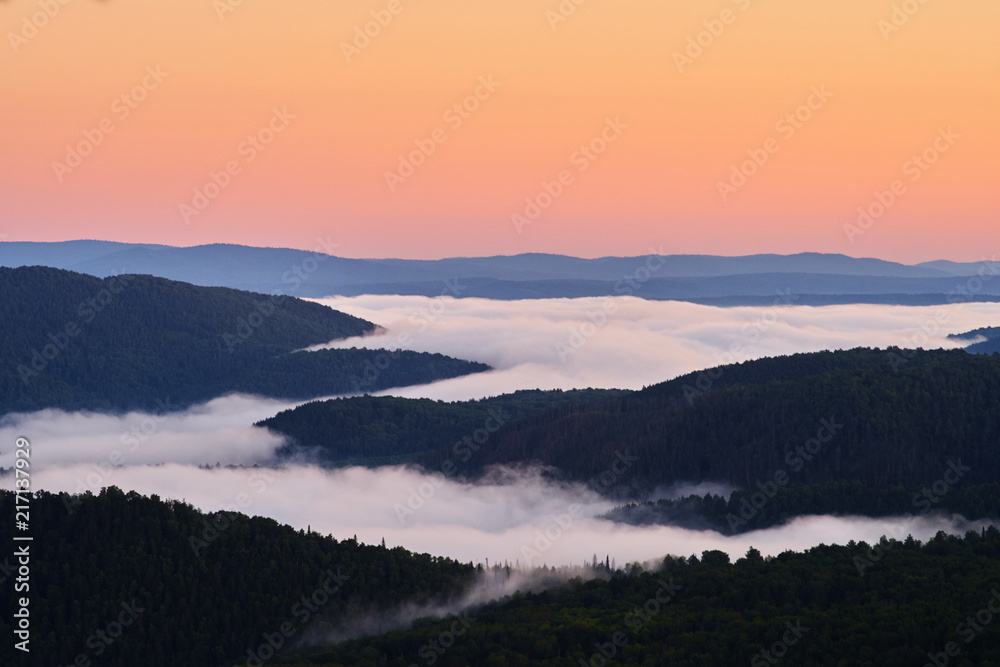 Dawn on top of the mountain. The fog at the bottom