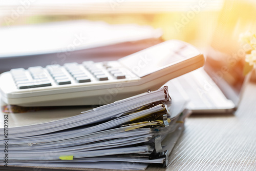 Stacks of papers documents files information business report papers, piles of unfinished document achieves with calculator laptop computer desk in modern office, Accounting planning budget concept