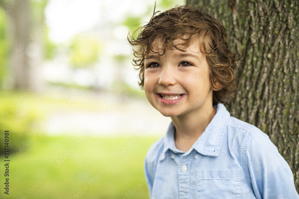 Cute Caucasian boy happily close to a tree Cute Caucasian boy happily close to a tree