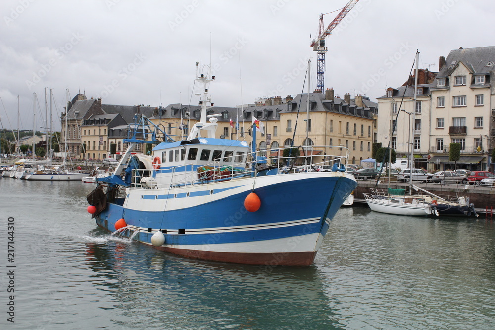 a fisher boat on its way in the port of dieppe in summer