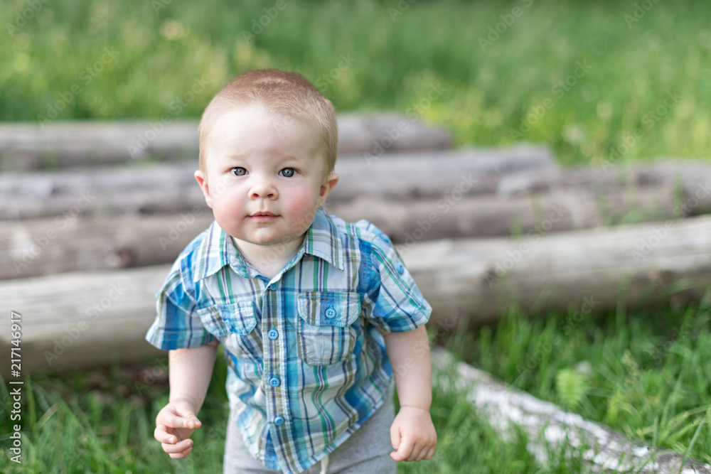Baby boy stands near the logs in the village Baby boy stands near the logs in the village