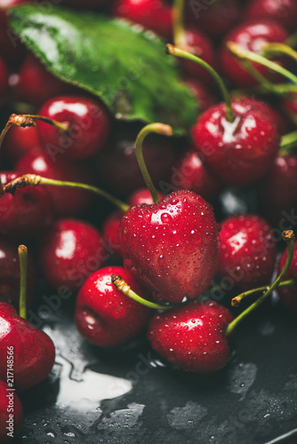 Fresh sweet cherry texture, wallpaper and background. Wet sweet cherries with leaves on dark background, selective focus, close-up. Summer food or local market produce concept