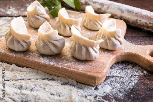 Pelmeni cooking on a board and wooden background, national Russian cuisine, vareniki, banner