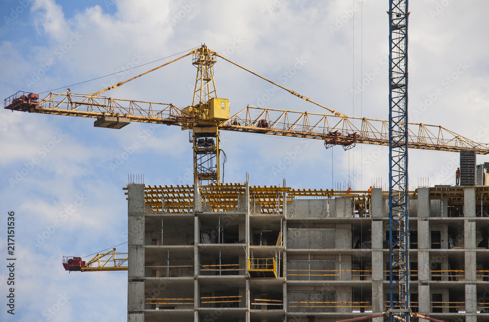 Crane and building under construction against blue sky.