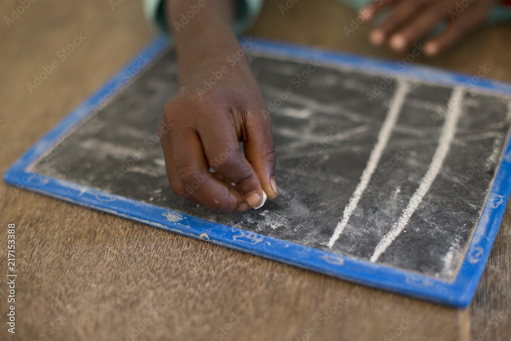 Mano de niño pintando en pizarra en una escuela de Gambia, Africa Mano de niño pintando en pizarra en una escuela de Gambia, Africa
