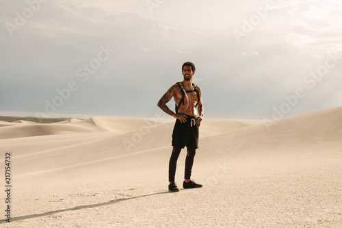 Fitness man standing on sand dune during workout