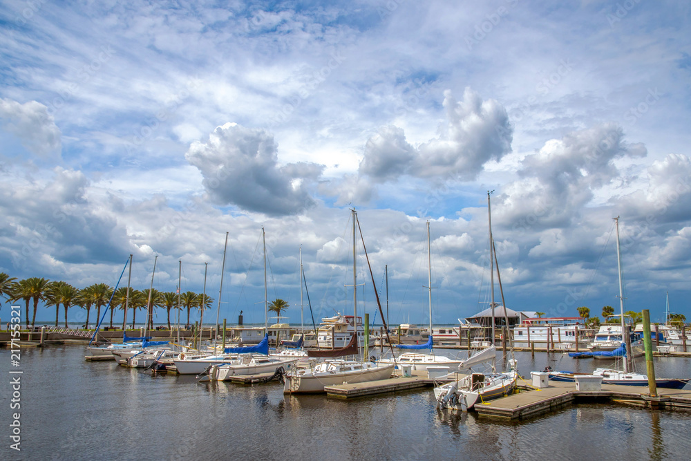 Yacht parking, against the sky with clouds. In the distance, a number of palm trees are visible. Scenic view.