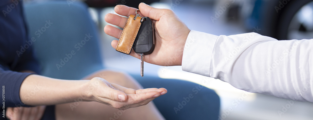 Panorama and close-up of car seller's hand giving keys to buyer